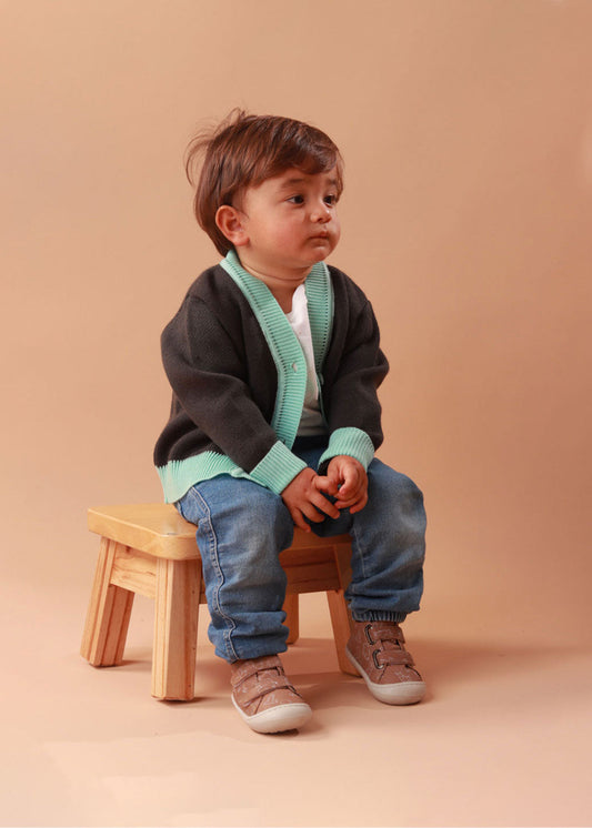 Bebé usando zapatos respetuosos para bebé color café con diseño de animales, mientras da sus primeros pasos con total comodidad y seguridad.
