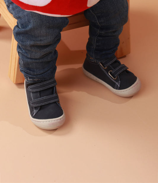 Bebé usando zapatos respetuosos azules pre-caminadores con diseño de animales, ideales para los primeros pasos. Imagen 1.