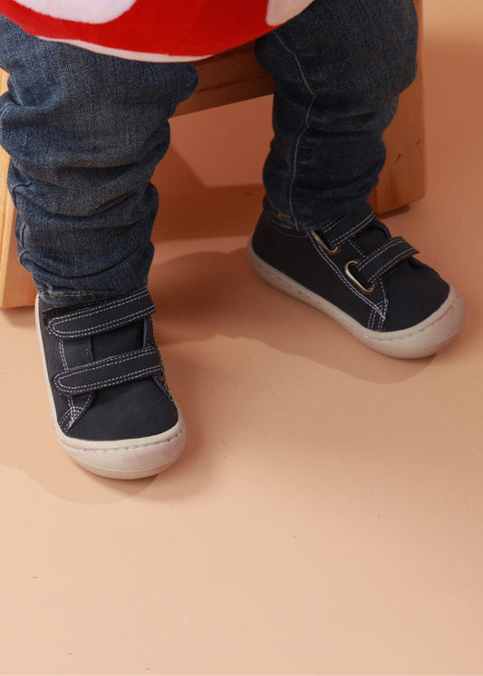 Bebé usando zapatos respetuosos azules pre-caminadores con diseño de animales, ideales para los primeros pasos. Imagen 1.