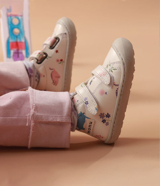 Bebé usando los zapatos respetuosos pre-caminadores Gatos Miau mientras da sus primeros pasos, con un ajuste cómodo y diseño flexible.